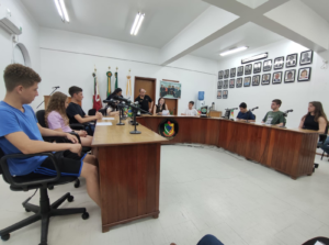 Jovens vereadores do Parlamento Juvenil 2024 sentados na bancada da Câmara Municipal, prontos para vivenciar a rotina legislativa em Novo Cabrais.